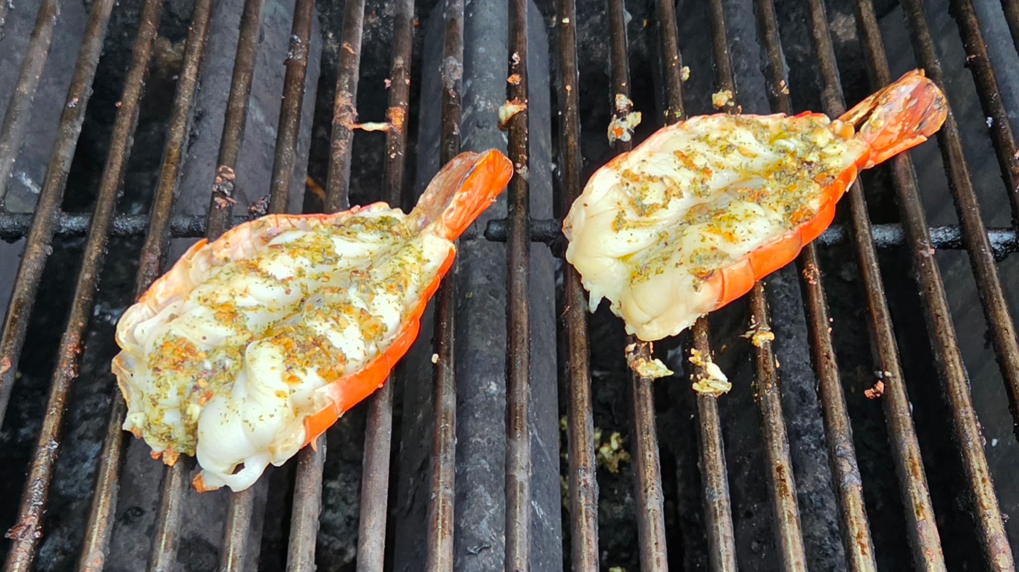 Split giant freshwater prawns cooking on a grill